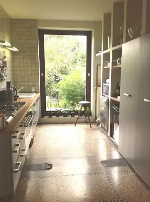 a kitchen with a window and a stool in front of it at Rez/duplex 3 ch et jardin in Brussels