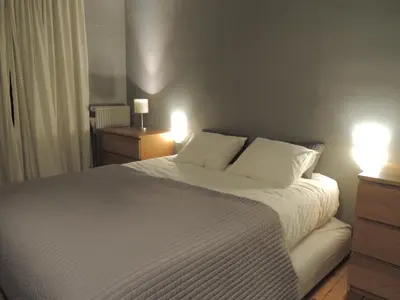 a bedroom with a large white bed with two lights at Rez/duplex 3 ch et jardin in Brussels