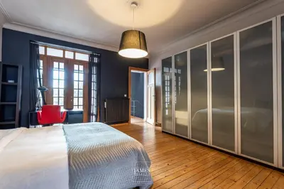a bedroom with a large bed and a red chair at Rez/duplex 3 ch et jardin in Brussels