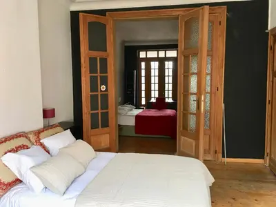a bedroom with a white bed and a door with a window at Rez/duplex 3 ch et jardin in Brussels