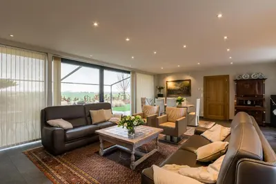 a living room with couches and a table at Polderwoning 'Cleylantshof' in Sint-Laureins
