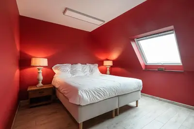 a red bedroom with a bed and a window at Polderwoning 'Cleylantshof' in Sint-Laureins