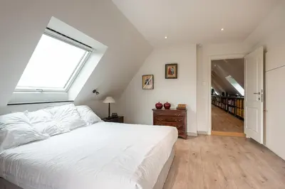 a bedroom with a large white bed and a window at Polderwoning 'Cleylantshof' in Sint-Laureins