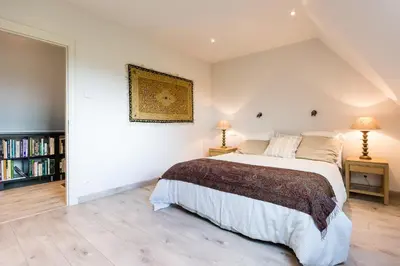 a bedroom with a large bed and a book shelf at Polderwoning 'Cleylantshof' in Sint-Laureins