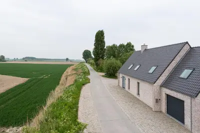 a house with a road next to a field at Polderwoning 'Cleylantshof' in Sint-Laureins