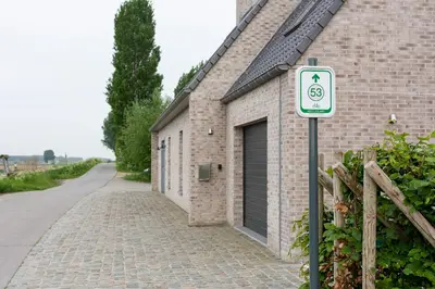 a brick building with a handicapped parking sign next to a garage at Polderwoning 'Cleylantshof' in Sint-Laureins