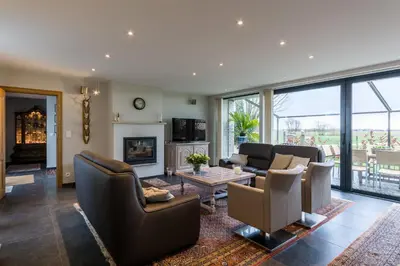 a living room with couches and a fireplace at Polderwoning 'Cleylantshof' in Sint-Laureins