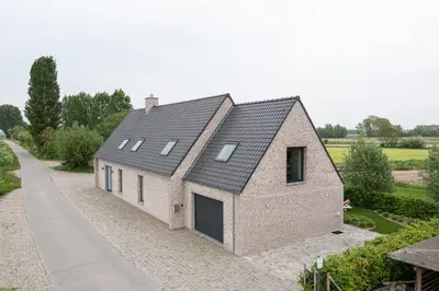 a large brick house with a black roof at Polderwoning 'Cleylantshof' in Sint-Laureins