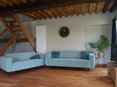 a living room with two blue couches and a clock at Logies Berckelaer in Sint-Gillis-Waas