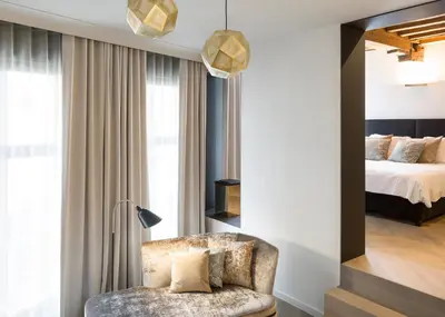 a bedroom with a bed and a chair in a room at Gulde Schoen Luxury Studio-apartments in Antwerp