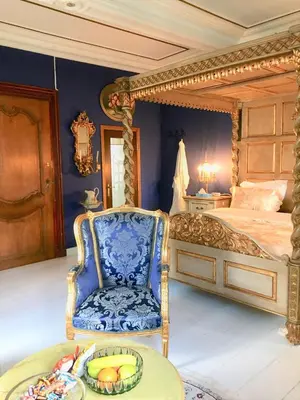 a bedroom with a bed and a chair and a table at Koetshuis Bosdam in Beveren