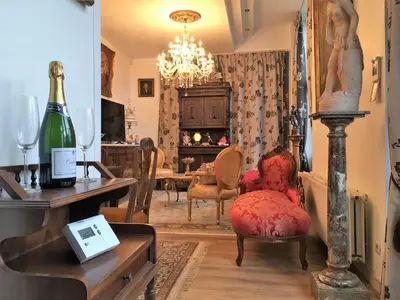 a living room with chairs and a table with a bottle of wine at Koetshuis Bosdam in Beveren