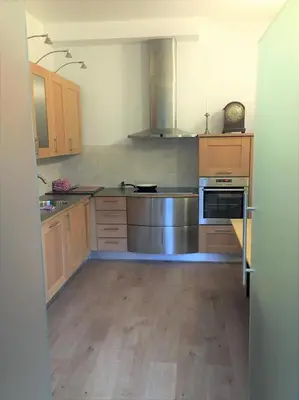 a kitchen with wooden cabinets and a stainless steel appliance at Koetshuis Bosdam in Beveren