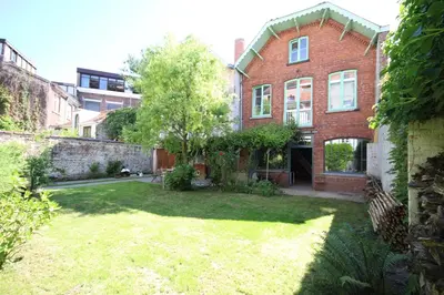 an old brick house with a yard in front of it at La maison du fond du jardin in Brussels