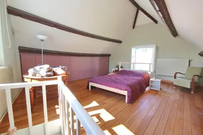 a bedroom with a bed and a wooden floor at La maison du fond du jardin in Brussels