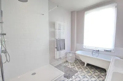 a white bathroom with a tub and a window at La maison du fond du jardin in Brussels