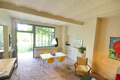 a living room with a table and yellow chairs at La maison du fond du jardin in Brussels