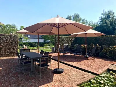 a table and chairs under an umbrella on a patio at B&B Tolkantoor in Zelzate