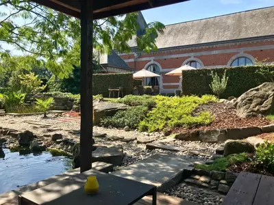 a garden with a pond in front of a building at B&B Tolkantoor in Zelzate