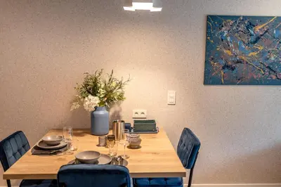 a wooden table with chairs and a vase of flowers at Abalona Hotel & Apartments in Dendermonde
