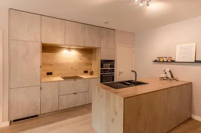 a kitchen with wooden cabinets and a counter top at Abalona Hotel & Apartments in Dendermonde