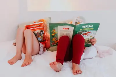 two girls laying on a bed reading books at Hotel Jerom in Kalmthout