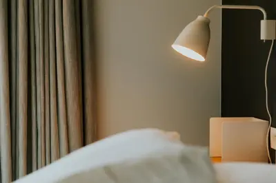 a bedroom with a bed with a lamp and a curtain at Hotel Jerom in Kalmthout