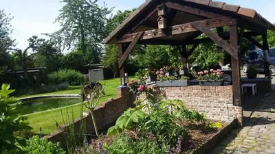 a garden with a wooden pergola and a pond at 't Vliethuys in Zwijndrecht