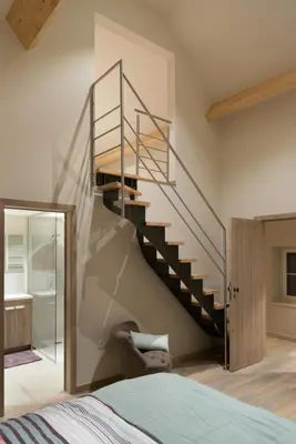 a spiral staircase in a bedroom next to a bed at B&B De Windheer in Sint-Martens-Lennik
