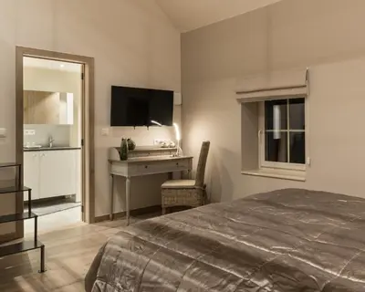 a bedroom with a bed and a desk with a television at B&B De Windheer in Sint-Martens-Lennik