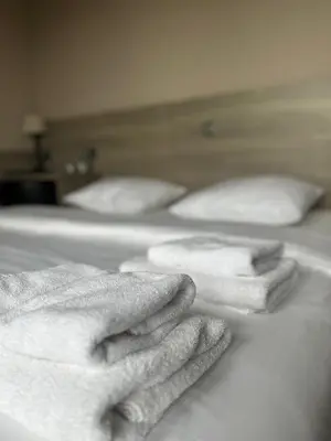 three beds with white towels stacked on them at Hotel Arriate in Lochristi