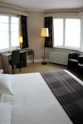 a hotel room with a bed and a desk and windows at Hotel Arriate in Lochristi