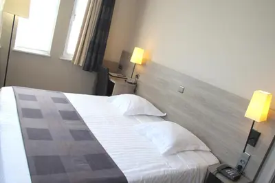 a hotel room with a bed with white sheets and pillows at Hotel Arriate in Lochristi