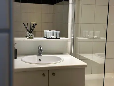 a white bathroom with a sink and a shower at Hotel Arriate in Lochristi