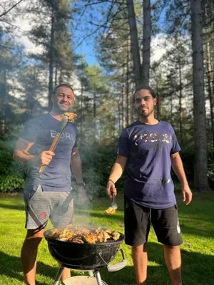 two men standing next to a barbecue grill at Luxe vakantiehuis in het bos in Overbroek