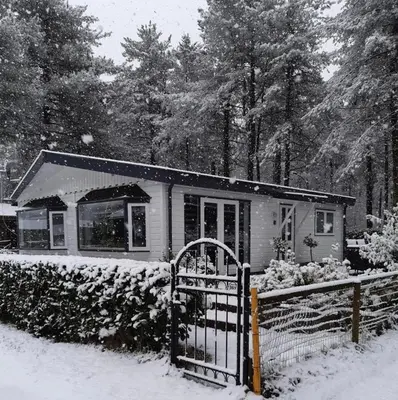 a house with a fence in the snow at Luxe vakantiehuis in het bos in Overbroek