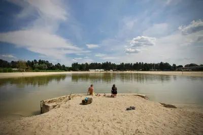 a couple of people standing on a beach in the water at Luxe vakantiehuis in het bos in Overbroek