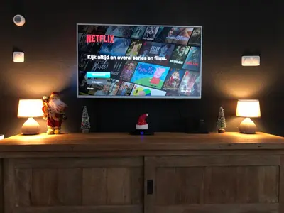a tv on a wall with two lamps on a table at Luxe vakantiehuis in het bos in Overbroek