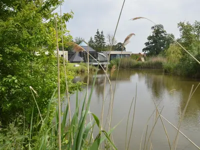 a view of a river with a house in the background at Lovely holiday home 'Walleken' with a pond in Eekhout