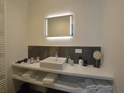a bathroom with a sink and a mirror and towels at Lovely holiday home 'Walleken' with a pond in Eekhout