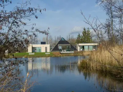 a house with a pond in front of it at Lovely holiday home 'Walleken' with a pond in Eekhout