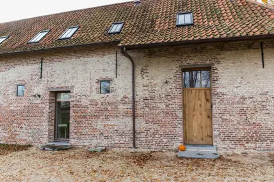 a brick building with a large wooden door at Clayshoeve in Munte