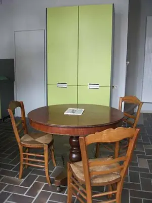 a wooden table with two chairs and a green cabinet at Geldmunt Apartment in Ghent