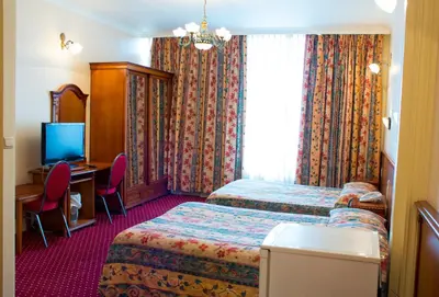 a hotel room with two beds and a desk and a television at Hotel Continental Gare du Midi in Brussels