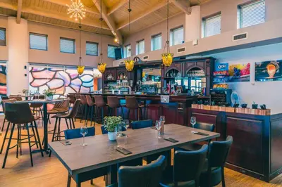 a restaurant with tables and chairs and a bar at EuroParcs Zilverstrand in Mol