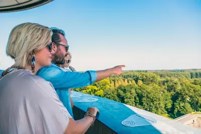 a man and a woman pointing at the sky with a surfboard at EuroParcs Zilverstrand in Mol