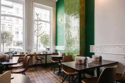 a restaurant with tables and chairs and a green wall at Charlie's Bed & Breakfast in Antwerp