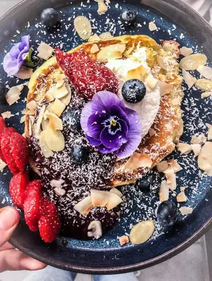 a plate of pancakes with fruit and flowers on it at Charlie's Bed & Breakfast in Antwerp