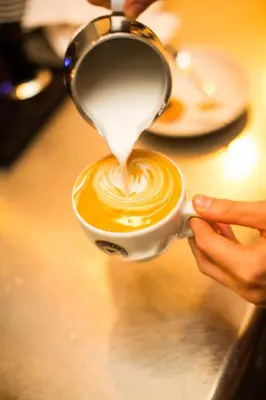 a person is pouring milk into a cup of coffee at Charlie's Bed & Breakfast in Antwerp