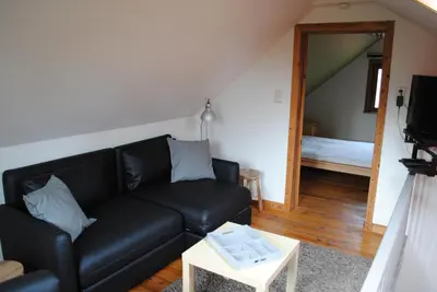 a living room with a black couch and a table at 't Huizeke in Asse